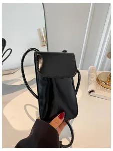Black glossy vertical cell phone bag detail showing sleek texture and refined strap design