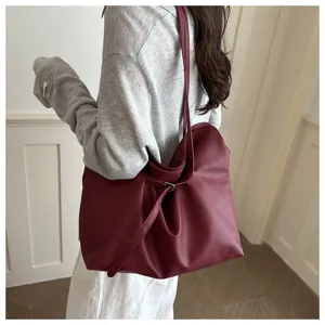 Detail shot of the wine red slouchy leather tote bag showing shoulder strap and belt.