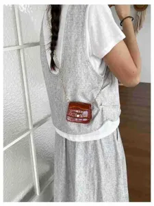 Detail shot of a mini brown crocodile pattern crossbody bag with metal chain strap.