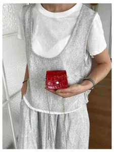 Detail view of a mini red crocodile pattern cross-body bag, fashionable lipstick pouch.
