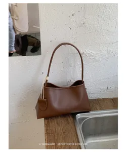 Detail view of brown retro underarm bag showing minimalist leather texture and stylish strap.