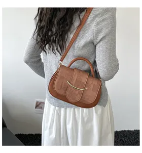 Vista de detalle de un bolso de hombro marrón retro patchwork con hebilla metálica curva.