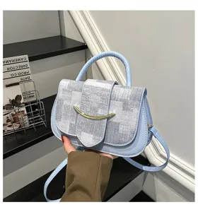 Bolso cruzado azul chic con cierre de barra metálica y solapa de tweed a cuadros.