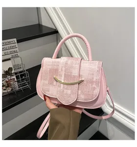 Detalle de bolso de mano cuadrado pequeño de cuero PU rosa con cierre curvo de metal.