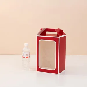 Red paper gift box with handle and clear window next to a water bottle for scale reference