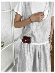Detailed shot of a stylish mini crossbody bag in dark red with crocodile pattern and chain strap.