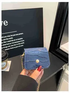 Mini blue croc-embossed crossbody bag detail, stylish gold chain and snap closure design.
