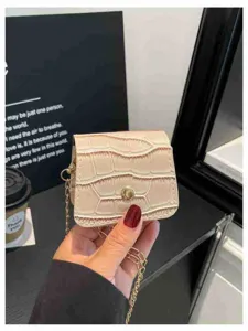 Mini faux leather crossbody bag detail shot, elegant stone pattern with gold chain strap.