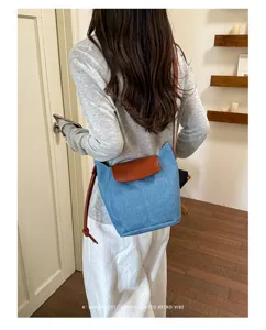 Elegante bolso cubo de denim para mujer con solapa de cuero marron para uso diario.