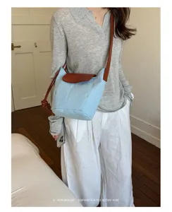 Vista detallada del elegante bolso de hombro tipo cubo para mujer en lona y cuero celeste.