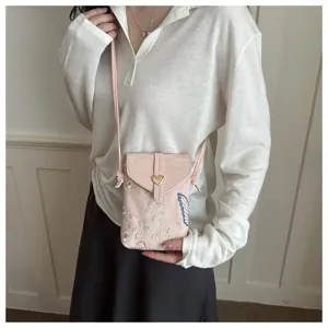 Vista dettagliata di una elegante borsa a tracolla rosa ricamata per telefono con fibbia.