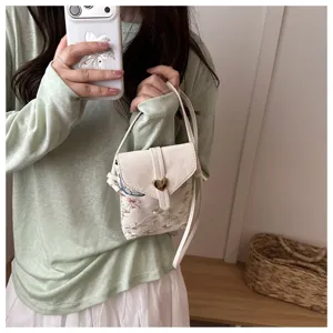 Vista ravvicinata della mini borsa telefono ricamata in stile cinese con dettagli floreali.
