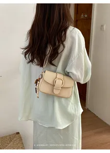 Detailed view of stylish retro beige woven shoulder bag with chic metal buckle and charm.