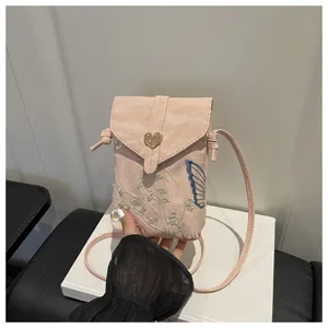 Vista dettagliata della borsa a tracolla per telefono ricamata rosa con chiusura a cuore.