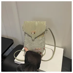 Primo piano dettagliato e raffinato della borsa a tracolla verde chiaro ricamata con fiori.
