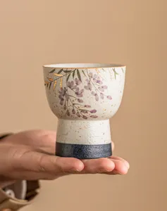 Hand-painted ceramic tea cup detail, featuring delicate wisteria floral pattern and gold trim.