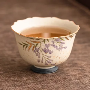 Exquisite ceramic tea cup with elegant wisteria and gold tracing design for home tea tasting.