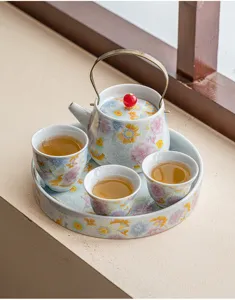 Charmant service à thé en céramique avec théière, tasses et plateau au motif floral coloré.