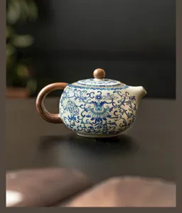 Vista detallada de una tetera Xishi de cerámica azul y blanca con mango y pomo de madera.