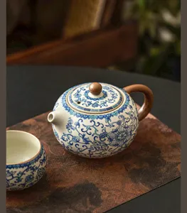 Exquisito detalle de tetera de porcelana azul y blanca con diseño de loto y mango de madera.