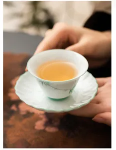 Close-up detail of traditional ceramic tea cup with hand-painted green bamboo design.