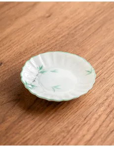 Hand-painted green bamboo ceramic tea cup pad, delicate fluted edge snack dish detail view.
