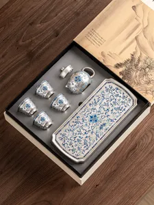 Vista dettagliata del set regalo da tè kung fu argentato con motivi floreali blu e vassoio.