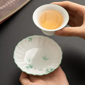 Hand-painted ceramic tea cup and saucer set with green bamboo pattern and floral edge design.
