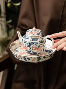 Close-up detail of the ceramic silver-plated teapot and saucer with goldfish pattern.