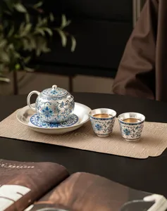 Detailed close-up of a silver-plated ceramic kung fu tea set with blue floral pattern.
