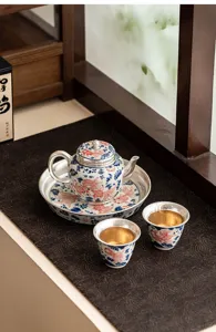 Detailed view of a silver-plated Chinese tea set with goldfish pattern, teapot and cups.