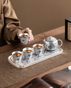 Dettaglio set da tè kung fu loto in argento 999 con teiera, tazze e vassoio sul tavolo.