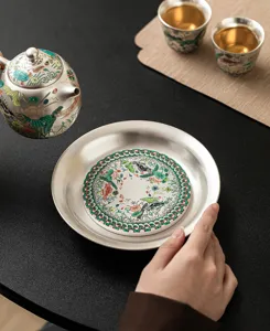Detail shot of exquisite silver tea set featuring traditional fish and lotus patterns.
