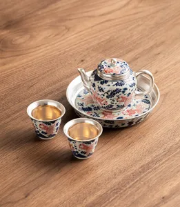 Gilt silver tea set featuring goldfish pattern, includes one teapot, two cups and tea tray.