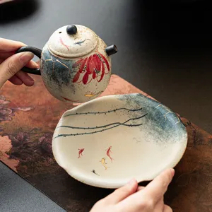 Hand-painted ceramic teapot and saucer set with lotus and koi design, elegant tea accessory.