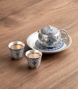 Detailed view of the silver-plated ceramic teapot and teacup set with blue floral pattern.