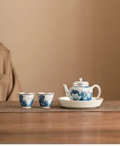 Detalle exquisito del juego de té de cerámica con baño de plata 999 y delicados motivos azules.