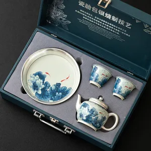 Juego de té de porcelana envuelta en plata 999 con tetera, tazas y platillo en elegante caja.