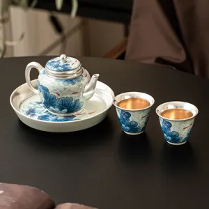 Elegante juego de té de cerámica plateada con diseño de loto azul, ideal como regalo.
