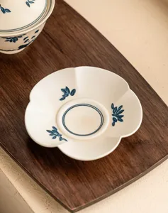 Handgeschilderde keramische thee kop schotel, bloemvormige blauwe bladeren thee mat detail.