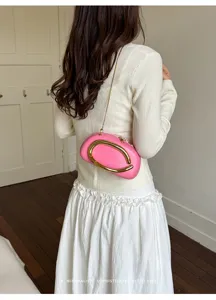 Detailed back view of a stylish pink mini clutch bag with a golden metal C-handle and chain strap.