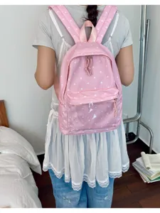 Detailed view of the pink polka dot backpack with a clear front pocket worn by model.