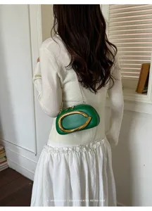 Green mini dome crossbody bag featuring a bold gold metal handle and stylish chain strap.