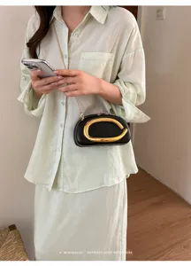 Chic black mini evening bag with striking gold metal abstract handle and sleek chain strap.
