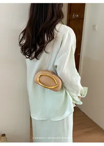 Minimalist retro mini round crossbody bag with metal handle, stylish evening shoulder purse.