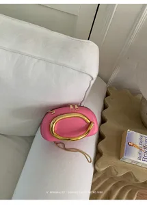 Pink minimalist shoulder bag with unique gold ring handle for women daily commute style.