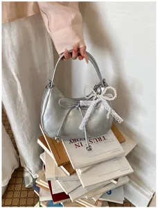 Vista ravvicinata della borsa hobo argento con fiocco in pizzo di perle e fiocco in pelle.