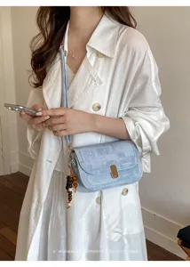 Gros plan détail du sac à bandoulière rétro bleu clair avec charm perles et fermoir en métal.