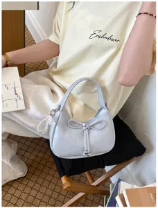 Dettaglio della borsa a tracolla azzurra di tendenza con fiocco e ciondolo di perle.