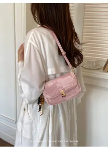Vue détaillée d'un sac à épaule rétro rose chic avec pendentif perles et fermoir dorés.
